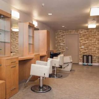 A modern hair salon interior featuring stylish chairs and mirrors against a brick wall.