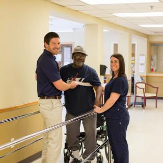 Healthcare professionals assisting a patient in rehabilitation.