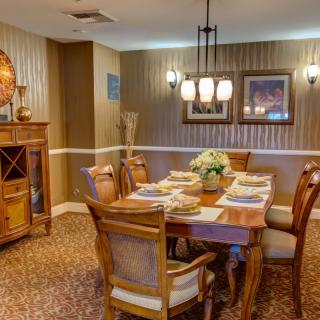 A warmly decorated dining room with wooden furniture and a chandelier, featuring a set dining table.