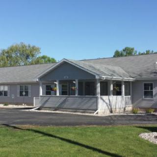 A single-story residential building with a front porch and driveway on a clear, sunny day.