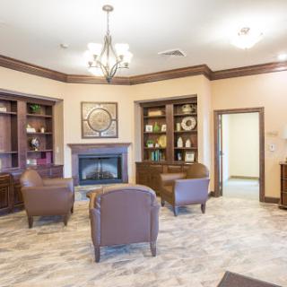 A cozy lounge area featuring comfortable seating, bookshelves filled with items, and a warm fireplace.