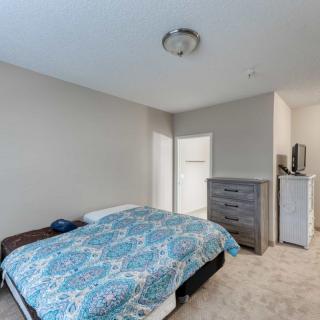 A spacious minimalist bedroom with a bed, dresser, and light fixture.