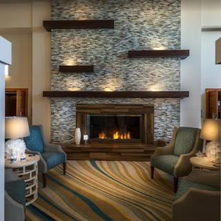 A modern living room with a stone fireplace, stylish shelving, and comfortable armchairs, creating a cozy atmosphere.