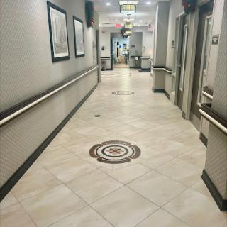 A well-lit, empty hallway featuring decorative tile patterns and framed artwork on the walls.