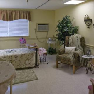 A cozy bedroom interior with floral bedding, an armchair, and decorative elements.