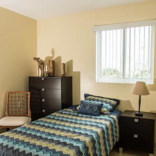 A cozy bedroom with a single bed, dresser, and window.