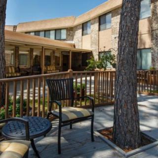 A cozy outdoor patio area with chairs and tables, surrounded by trees and adjacent to a building.