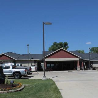 A suburban building with a parking lot and vehicles under a clear blue sky.