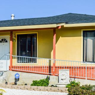 A yellow and orange house with a sloped roof and front yard.