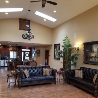 A cozy living room with elegant sofas, a chandelier, and wooden flooring.