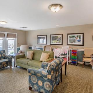 A cozy living room featuring comfortable seating, artwork on the walls, and warm lighting.