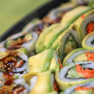 Close-up of sushi rolls topped with avocado slices.