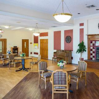 A spacious community room with round tables, chairs, and warm lighting.