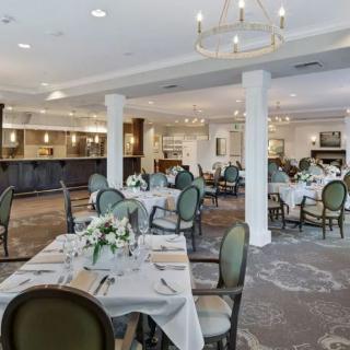 An elegant dining area with neatly arranged tables and chairs, adorned with floral centerpieces and illuminated by chandeliers.