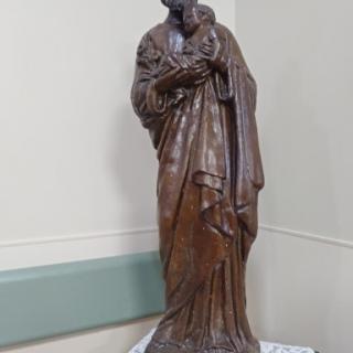 A wooden statue of a religious figure standing gracefully.
