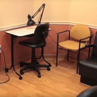 A small office space with a desk, chair, and lamp.