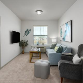 A cozy living room with modern furnishings, featuring a sofa, armchairs, and a large window.