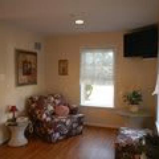 A cozy living room with an armchair, a small lamp, and wall decor.