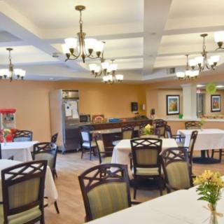 A well-lit dining area with multiple tables and chairs, adorned with chandeliers and a popcorn machine in the corner.