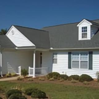 A suburban residential house with a pitched roof and white siding.