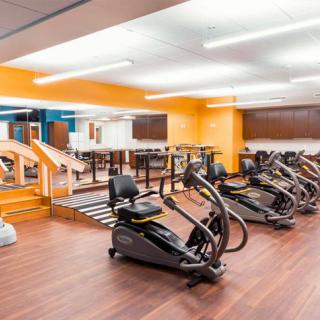 A spacious gym with various exercise machines and bright, modern decor.