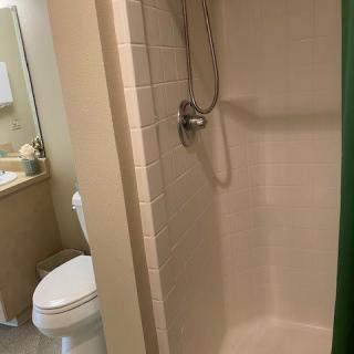 A small bathroom featuring a shower, toilet, and sink with a mirror.