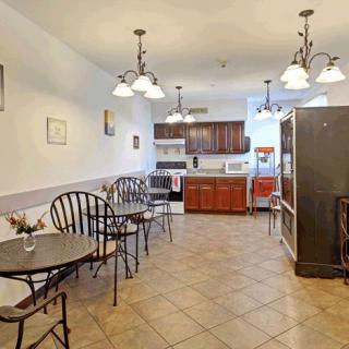 A spacious kitchen and dining area with multiple tables and chairs, featuring modern lighting fixtures and appliances.