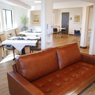A modern living and dining area with a brown leather sofa and neatly arranged tables.