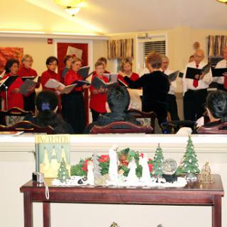 A choir performing during a festive gathering, surrounded by holiday decorations.
