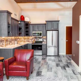 A modern kitchen with sleek cabinetry and red armchairs, featuring stainless steel appliances.