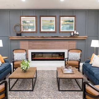 A modern living room with stylish seating and a central fireplace, accented by artwork on the walls.
