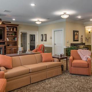 A cozy living room with comfortable seating, warm lighting, and a bookshelf.