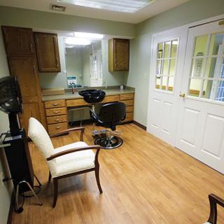 A cozy hair salon interior featuring a hairdressing station with mirrors and chairs on a wooden floor.