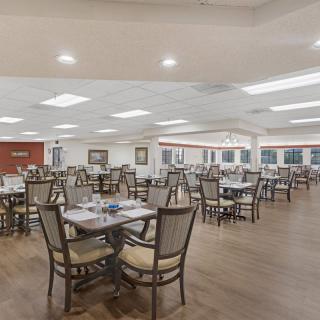A spacious dining area with neatly arranged tables and chairs, featuring bright overhead lighting.