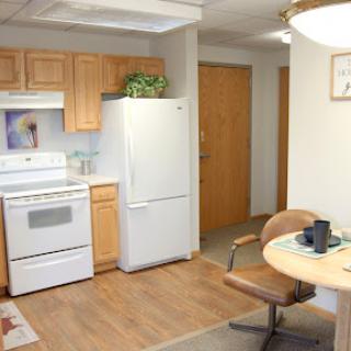 A cozy kitchen and dining area with wooden cabinets, a white refrigerator, and a round table set for a meal.