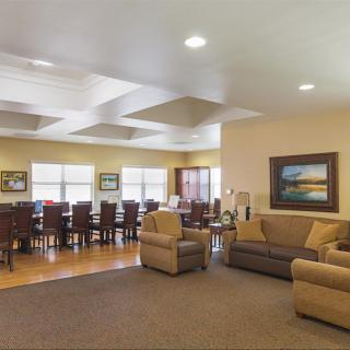 A spacious living room with a dining area featuring sofas, armchairs, and a large table.