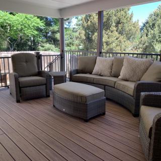 A cozy outdoor patio with cushioned seating and wooden flooring, perfect for relaxation.