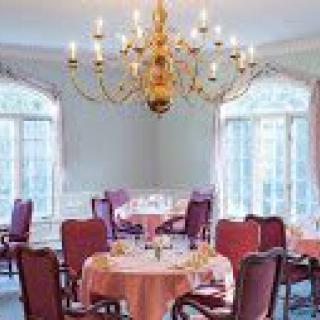 An elegant dining room with a large chandelier and multiple tables set for dining.