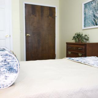 A cozy bedroom with a neatly made bed and wooden furniture.