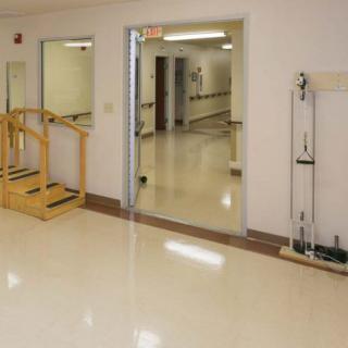 A clean and empty hallway with a small flight of stairs and open doors leading to another corridor.