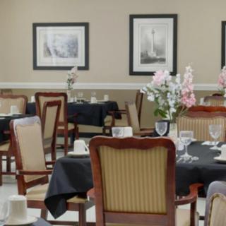 An elegant dining room with neatly arranged tables and chairs, decorated with flowers and framed art on the walls.