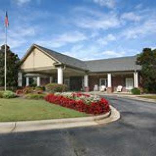 A well-maintained building entrance with a landscaped driveway and flower beds.