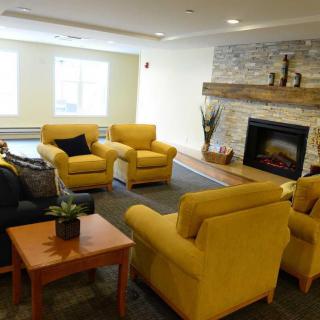 A cozy living room with yellow chairs and a stone fireplace.