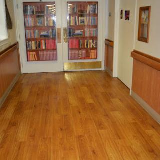 A hallway leading to a library with wooden flooring and shelves filled with books.