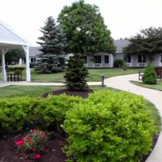 A well-maintained garden with a walkway surrounded by shrubs and trees, leading to residential buildings.