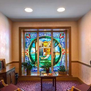 A room featuring a vibrant stained glass window with seating and indoor plants.