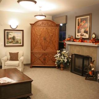 A cozy living room with a fireplace, armchair, and wooden cabinet.