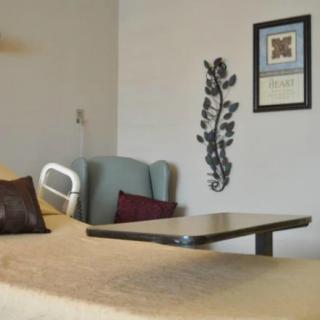 A hospital room with a medical bed, an armchair, and wall decorations.