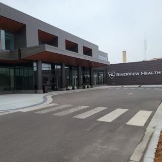 A modern healthcare facility showcasing contemporary architecture, complete with a landscaped entrance and designated pedestrian crossing.