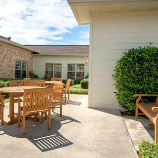 A sunny patio area with wooden furniture and greenery.